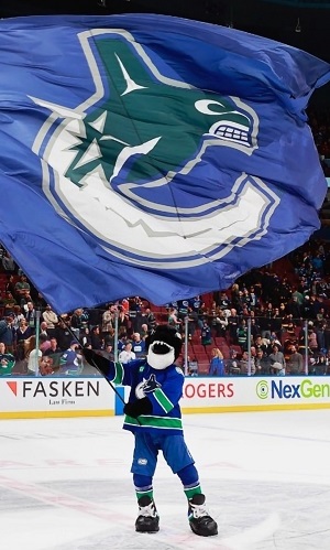 Fin the orca standing on the ice waving a Canucks flag