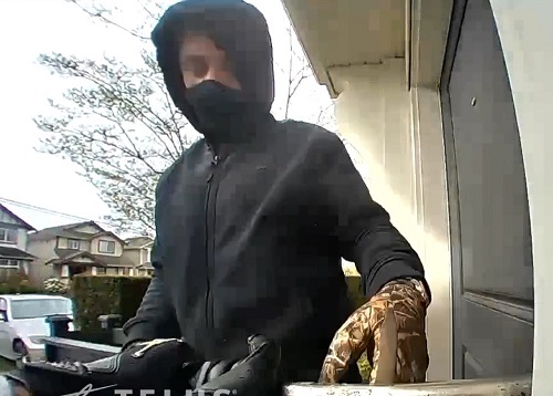 Photo d'un suspect portant un sweat à capuche noir et un masque noir avec un gant de camouflage visible