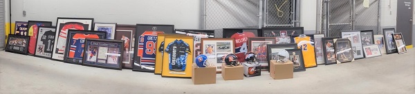 Dozens of recovered sports memorabilia including framed photos, jerseys, helmets and equipment all lined up in a row.