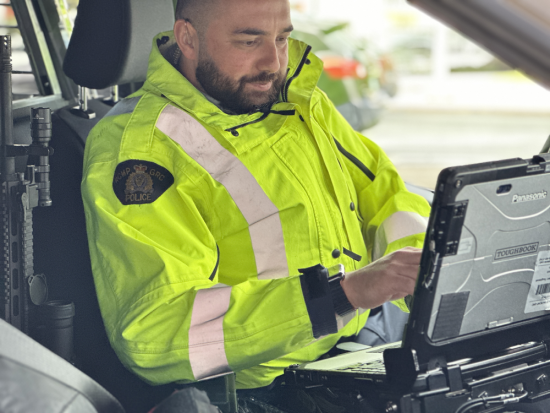 Un agent du Détachement de la GRC de Richmond assis dans une voiture de police prépare une contravention