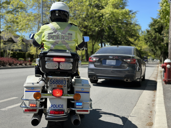 le caporal Peter Somerville effectue un contrôle routier sur sa motocyclette au bord de la route.
