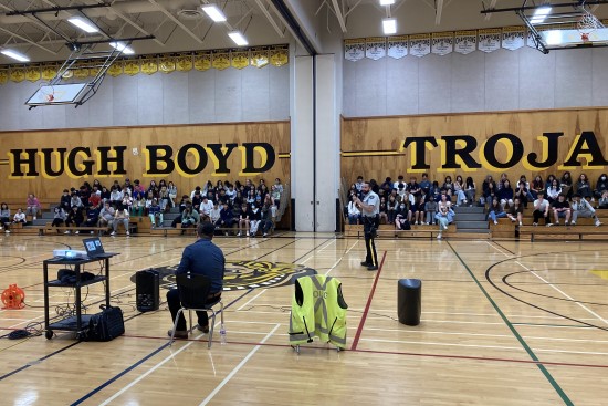 RCMP officer presenting to an audience of secondary students in the Hugh Boyd gymnasium