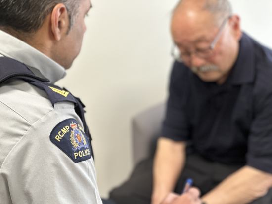 Corporal Sonny Virk of Richmond RCMP and a man sitting and talking together.