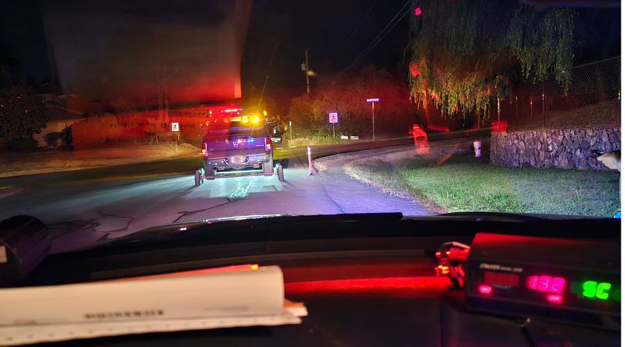 Photo from inside the police car of a truck being towed away. In the foreground a radar display reads "132"