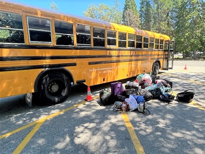 Photo of school bus parked with students' luggage next to it