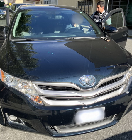 Black Toyota stopped with police officer talking to the driver