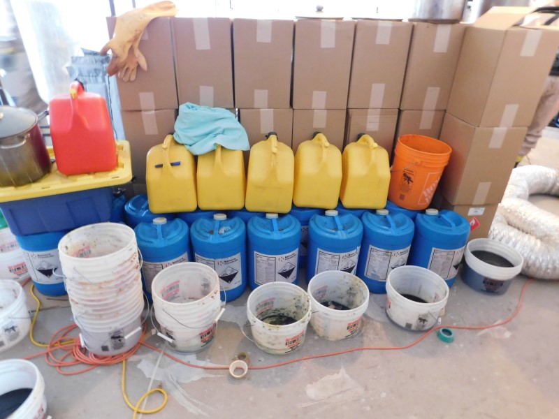 Boxes and containers of chemicals utilized to produce MDMA located within the synthetic drug lab