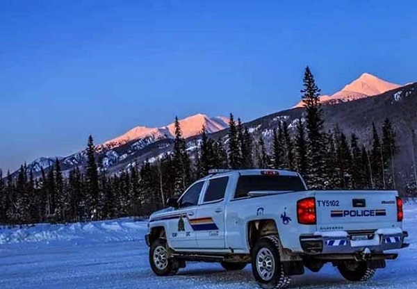 Camionnette de la GRC garée sur une route enneigée et montagnes enneigées en arrière-plan.