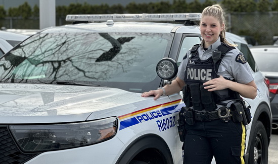 La gendarme Tara Joubert se tient à côté d’un véhicule de police identifié