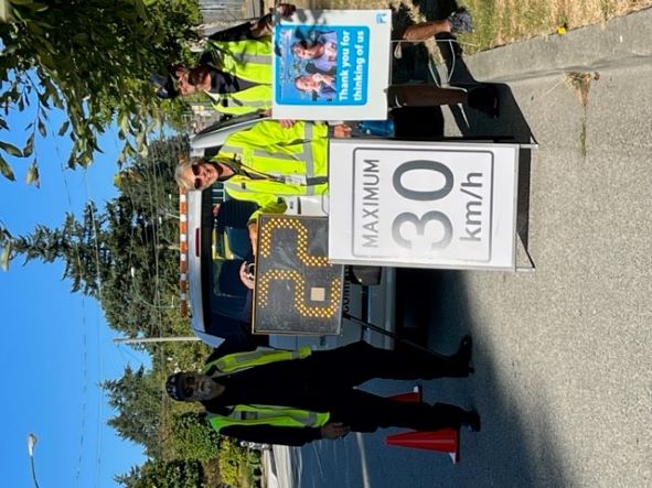 three police volunteers next to a speed board indicating 22 with a 30km/h sign