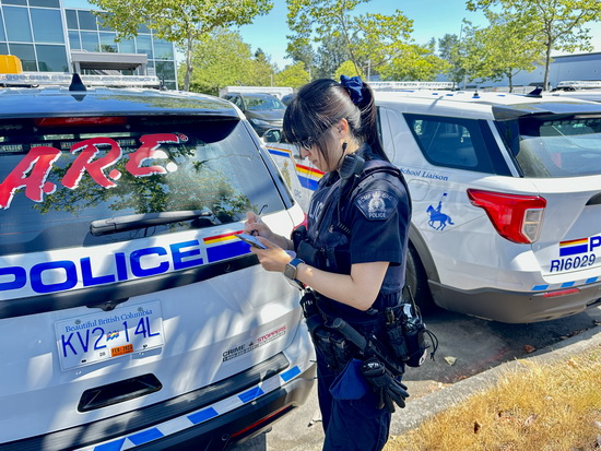 La gendarme Liu écrit dans son bloc-notes devant un véhicule de police