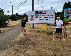 Board members Glen Atkins and John Hough with sign advertising the shredding event 