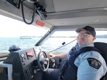 Photo of Cst. Harrision operating the Port Hardy police vessel to escort the canoe journey.