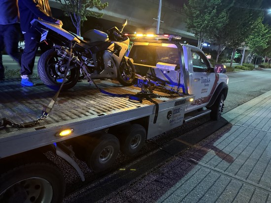 Motorcycle on top of flat bad tow truck at night