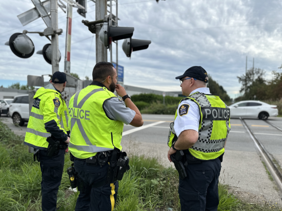 Un agent du Détachement de la GRC de Richmond se tient avec la Police du CN à un passage à niveau