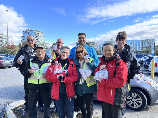 Le Détachement de la GRC de Richmond, des bénévoles et des partenaires communautaires sont debout ensemble, tenant des réflecteurs de sécurité pour piétons