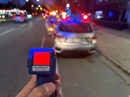 officer holding approved screening device showing FAIL during traffic stop