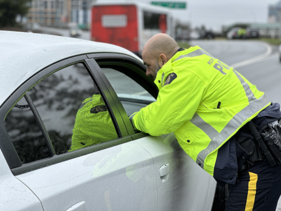 police officer in reflective jacket leaning into the passenger window of a vehicle