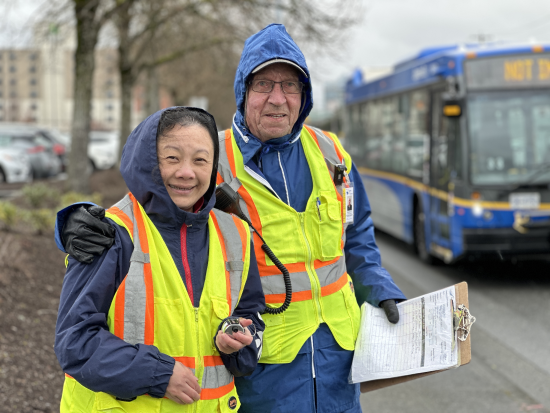 2 volunteers wearing rain jackets and holding a clipboard