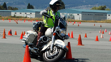 Officer riding a motorcycle around traffic cones