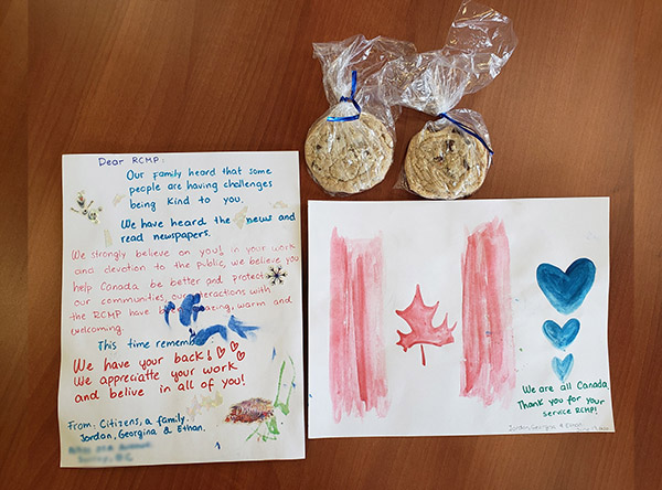 Une lettre, une carte et deux sacs de biscuits faits maison. Sur la carte, un drapeau du Canada et trois cœurs bleus sont peints côte à côte.