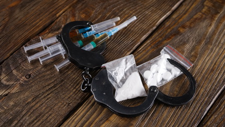 Photo of handcuffs and illicit drugs