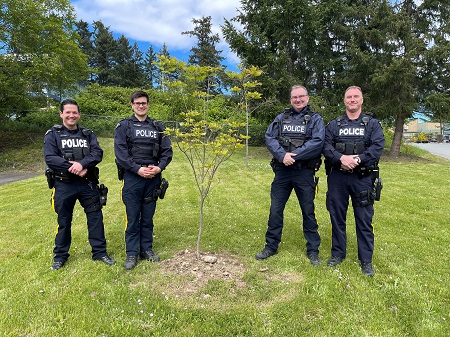RCMP officers standing next to a newly planted tree