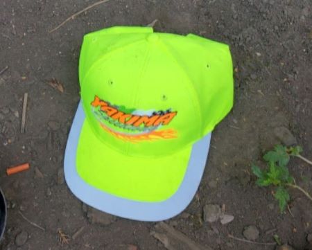 Photo d’un chapeau vert fluorescent portant une inscription orange et garni d’une bordure blanche.  