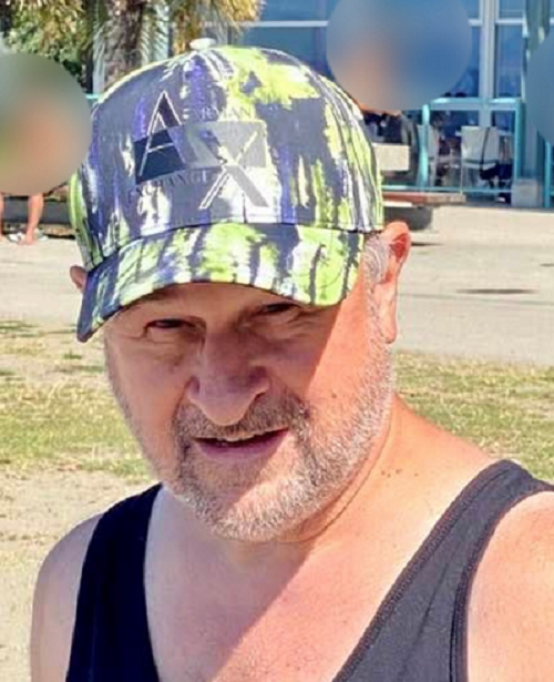 Photo of George Michas wearing a dark tank top and a grey, white and yellow baseball cap.