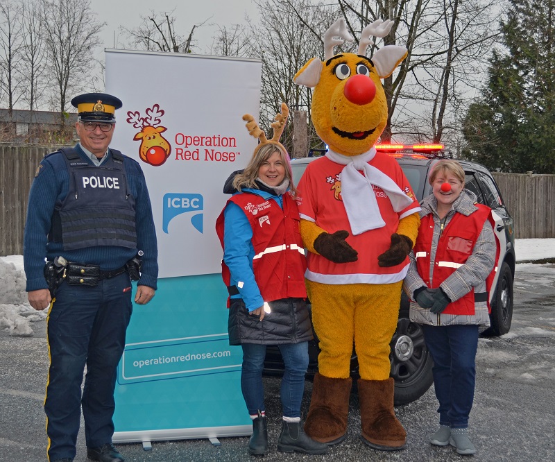 Police officer and operation red nose volunteers standing in front of a police vehicle