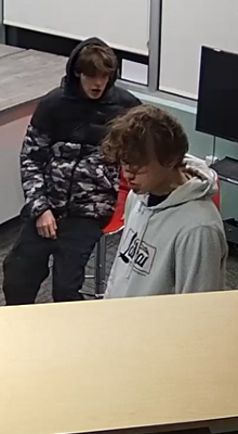 Two male youth walking inside a library.