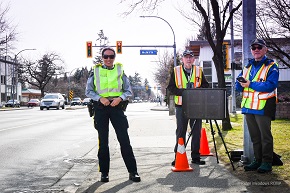 Femal police officer waerung a reflective vest and two speed watch volunteers working together
