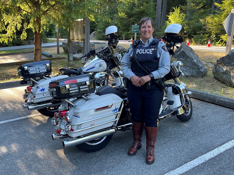 Constable Tania Saunders standing beside two RCMP motorcycles