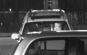Video-still photo of suspect sitting in the driver’s seat of a white Ford Escape