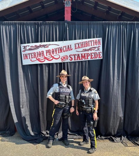 RCMP officers Cst. Valotaire and Cst. Taylor posing in front of an IPE banner.