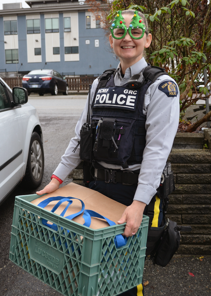 La gendarme Daniels, qui porte des lunettes en forme d’arbre de Noël, transporte des dons recueillis lors d’un événement Bourrer la voiture de police.