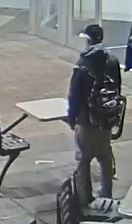 Surveillance still-image of the back of the suspect standing outside of the mall