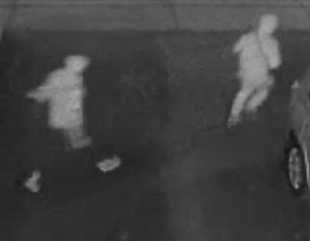 Une image floue, en noir et blanc, de deux personnes portant des chandails à capuchon ou des vestes qui sont en train de courir.