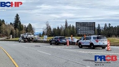 Photo of three police vehicles with a tow truck that is towing a pickup truck
