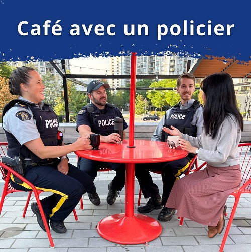 Des agents de police sont assis autour d’une table à l’extérieur, boivent un café et parlent avec le public.