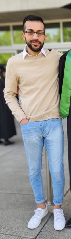 Photo of Jasdeep Parmar standing wearing cream coloured swetaer with white shirt collar, blue jeans, and white shoes